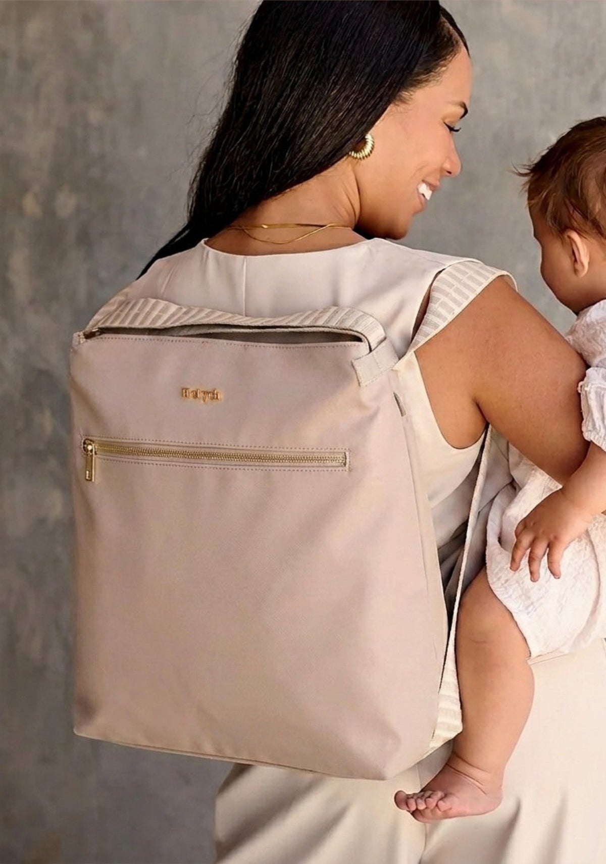 Mum carrying her baby with a taupe Heiych H-Convert worn as a backpack