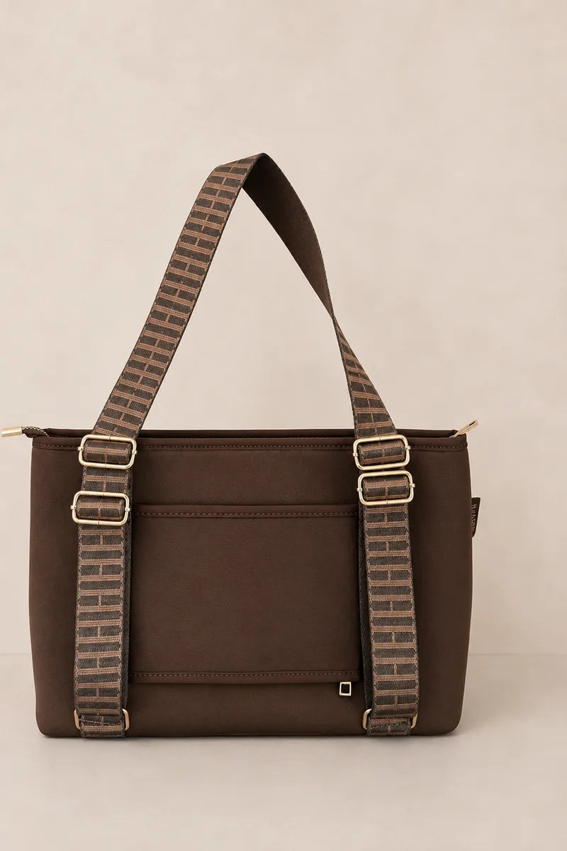 A chocolate brown tote bag with a matching brown and beige patterned shoulder strap and gold-tone hardware, shown against a solid light beige background.