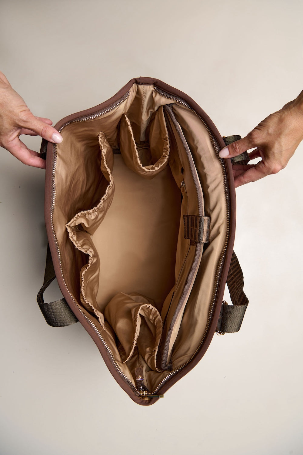 Brown chocolate bag with interior lining, held open by hands against a neutral background